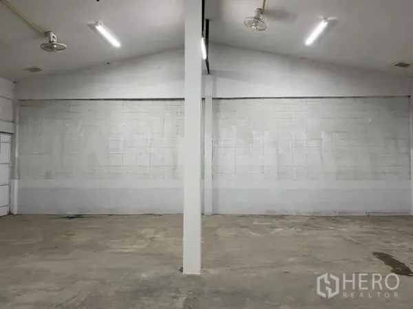 Warehouse for rent in Chatuchak, Bangkok - Bright open-plan warehouse interior with white block walls, central support column, concrete floor and LED lighting.