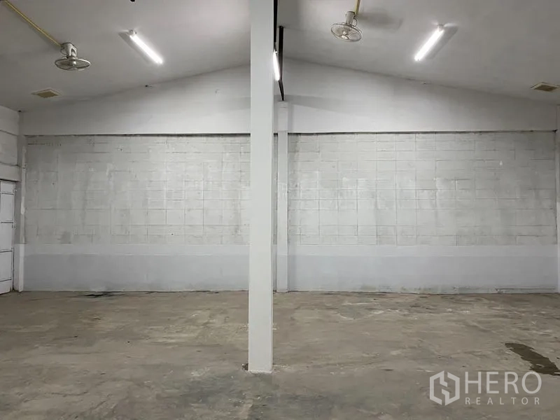 Warehouse for rent in Chatuchak, Bangkok - Bright open-plan warehouse interior with white block walls, central support column, concrete floor and LED lighting.