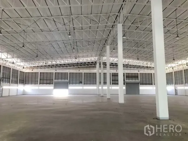 工厂 出租或出售在Phra Nakhon Si Ayutthaya - 高钢桁架屋顶的大型生产车间，白色立柱与平整混凝土地面。