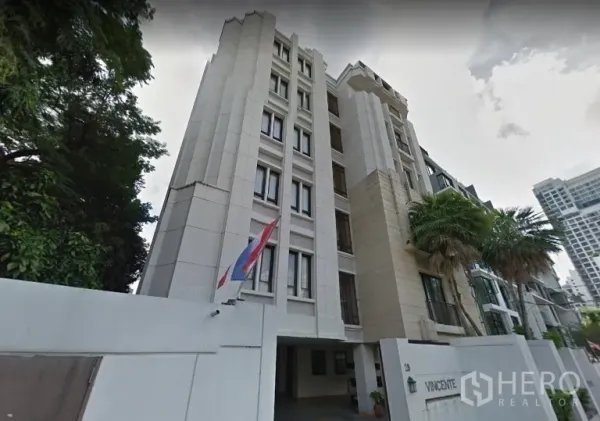 公寓 出售在Watthana, Bangkok - 低层公寓外观，带门禁入口与棕榈树，位于曼谷วัฒนา区。