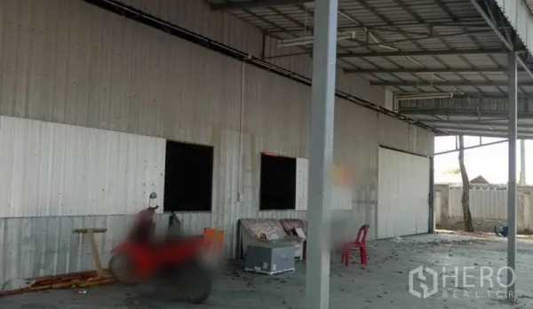 货栈 出租在Khlong Sam Wa, Bangkok - 仓库侧立面，波纹金属墙与屋檐雨棚，混凝土装卸平台开阔。