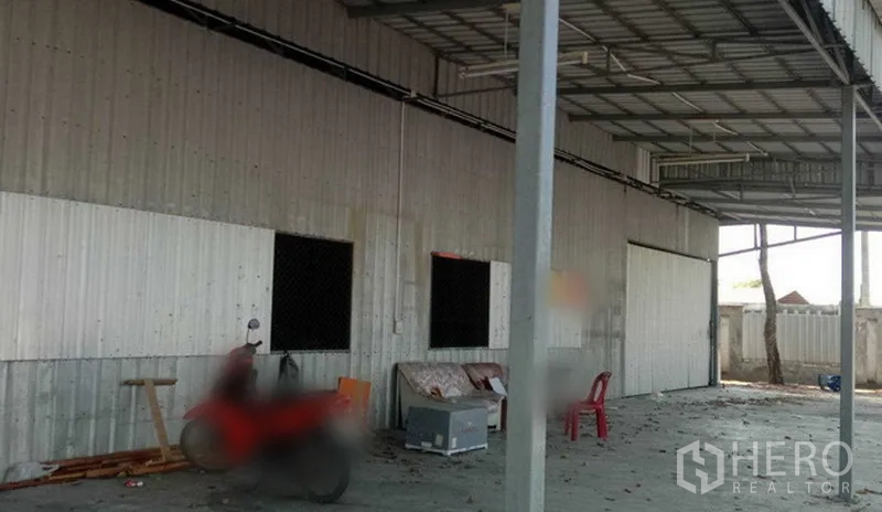 货栈 出租在Khlong Sam Wa, Bangkok - 仓库侧立面，波纹金属墙与屋檐雨棚，混凝土装卸平台开阔。