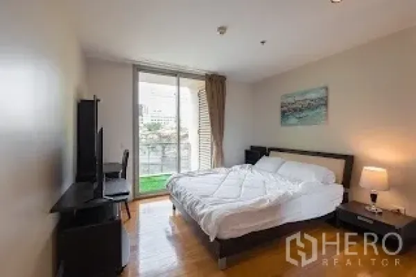 Condominium for rent in Bang Rak, Bangkok - Bedroom with large window and balcony access, bed and TV stand.