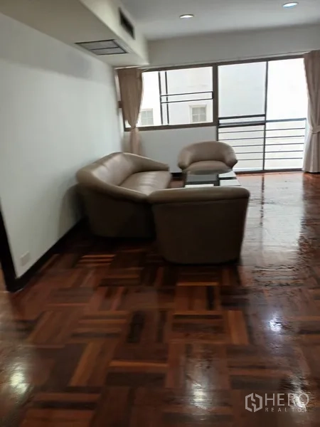 คอนโด ให้เช่าในDin Daeng, Bangkok - ห้องนั่งเล่นสว่าง โซฟาหนังสีเบจ โต๊ะกระจก และพื้นปาร์เกต์เงาใกล้หน้าต่างบานใหญ่