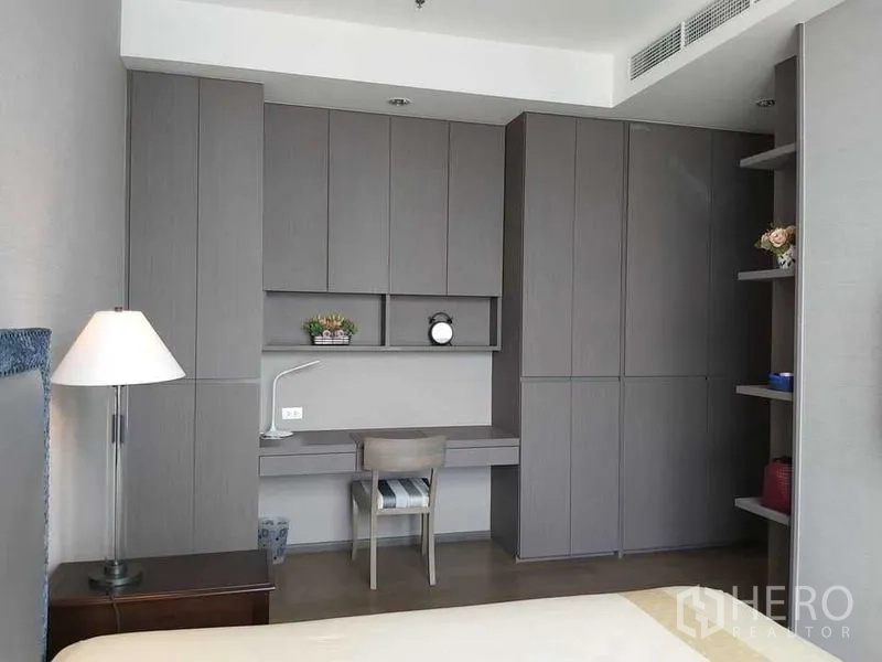 Condominium for sale in Bang Rak, Bangkok - Bedroom workspace with extensive built-in wardrobes, shelving, and a study desk.