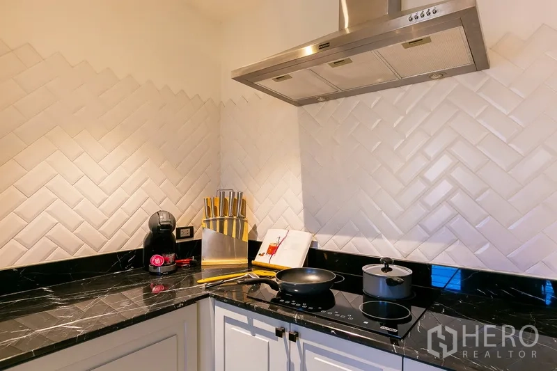 房间 出租在Khlong Toei, Bangkok - 封闭式厨房一角，黑色石材台面，电磁灶与抽油烟机。