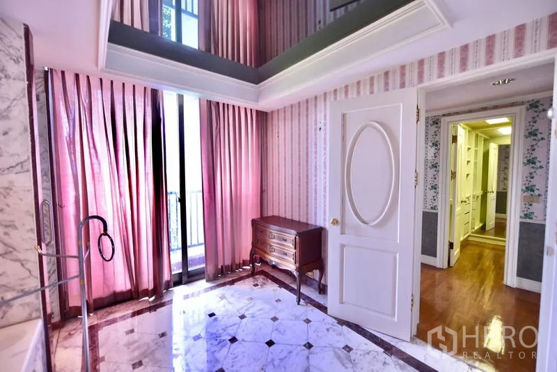 คอนโด ขายในPak Kret, Nonthaburi - โถงหรือมุมแต่งตัวปูหินอ่อน ม่านสีชมพูสูง พร้อมตู้ลิ้นชักและประตูออกสู่ทางเดิน