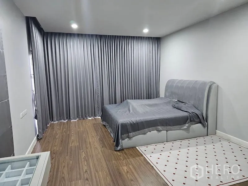 บ้าน ให้เช่าหรือขายในLam Luk Ka, Pathum Thani - ห้องนอนกว้าง ผ้าม่านสีเทา เตียงบุผ้าและพื้นไม้