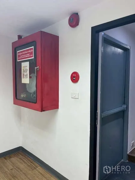 Office Space for rent - Fire safety cabinet, alarm, and emergency exit door in the office corridor.