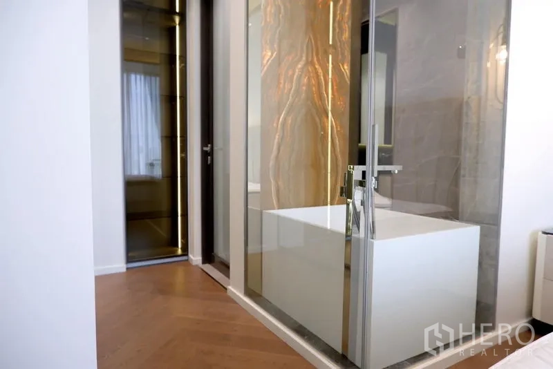 公寓 出租在Pathum Wan, Bangkok - 玻璃隔断后的独立浴缸，背光玛瑙装饰墙