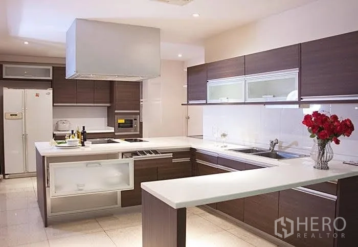 Condominium for rent in Yan Nawa, Bangkok - Modern U‑shaped kitchen with white countertops, dark wood cabinetry, island cooktop and built‑in appliances.