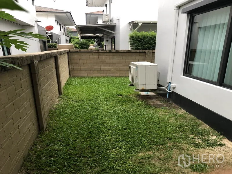 บ้าน ให้เช่าในBang Kapi, Bangkok - สนามหญ้าข้างบ้าน รั้วอิฐทึบ และคอมเพรสเซอร์แอร์ภายนอก
