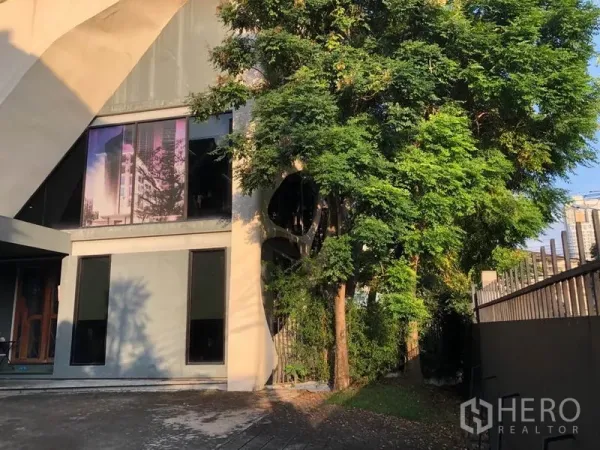 Office Space for rent in Khlong Toei, Bangkok - Side elevation of the office with large windows and mature trees by the fence.