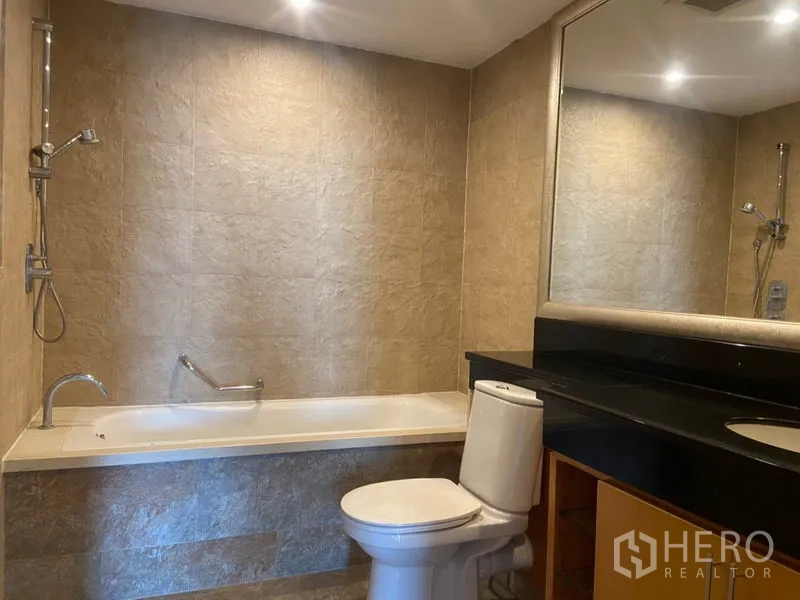 公寓 出租在Sathon, Bangkok - 浴室配浴缸、淋浴、大片镜面与石纹墙面。