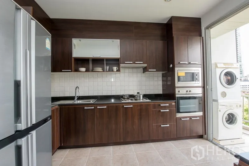 Condominium for rent in Sathon, Bangkok - Kitchen opening to a balcony with stacked washer and dryer plus city view.