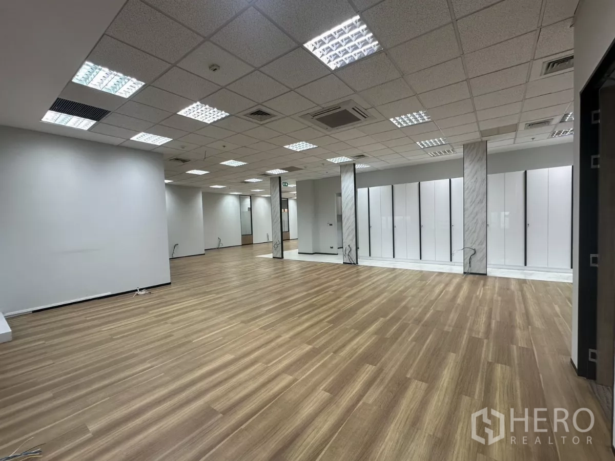 办公空间 出租在Watthana, Bangkok - 开放办公区，木地板、白色储物墙与网格吊顶灯。