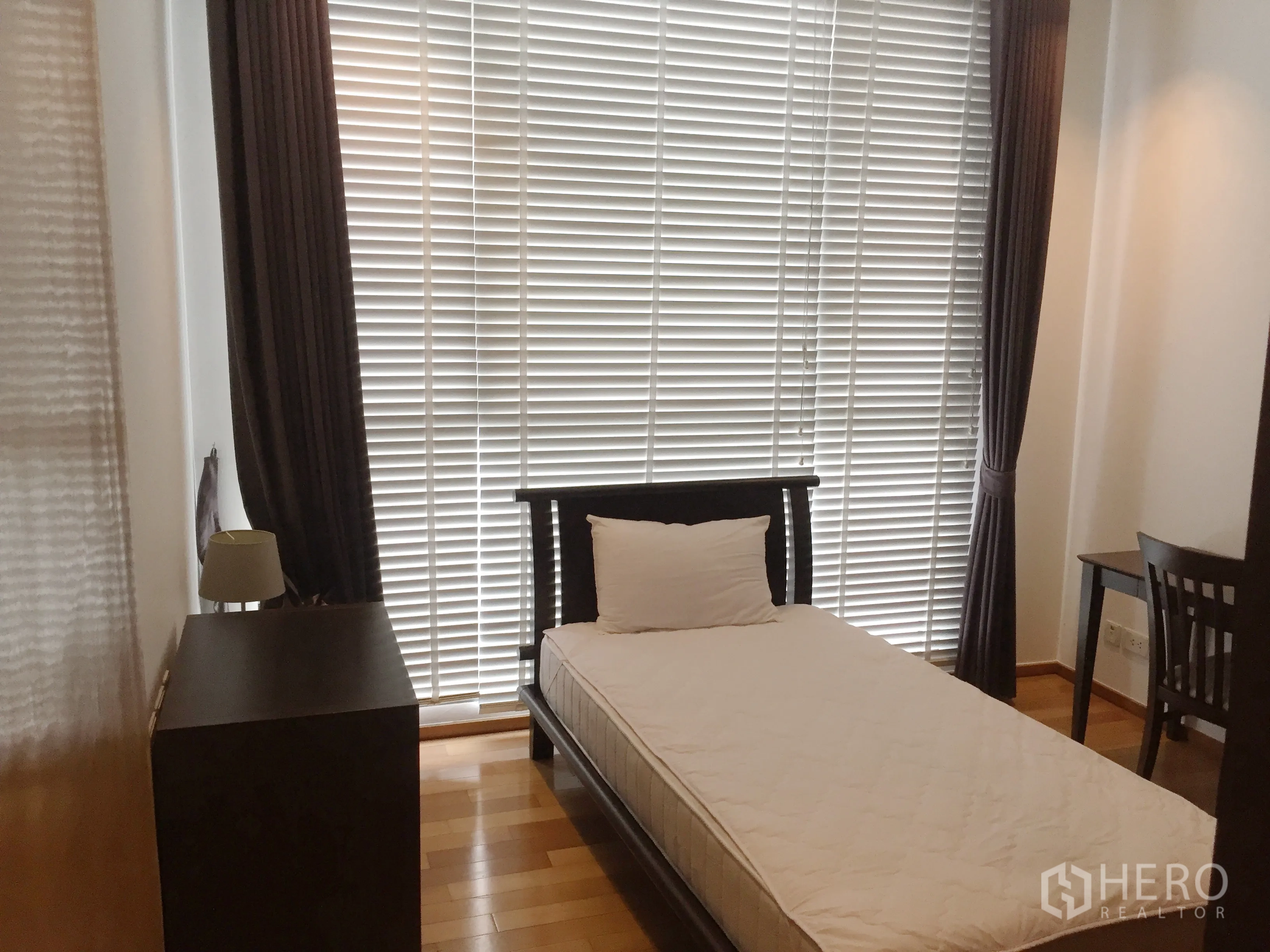 Condominium for rent or sale in Watthana, Bangkok - Cozy single bedroom with desk, chest of drawers and full-height window blinds.