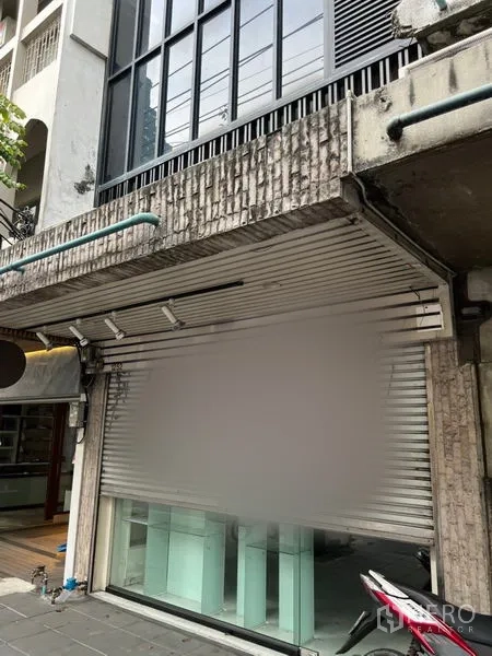 อาคารพาณิชย์ ให้เช่าในBang Rak, Bangkok - ด้านหน้าตึกแถวพร้อมประตูม้วนและกระจกโชว์สินค้า บนทางเท้าใจกลางเมือง