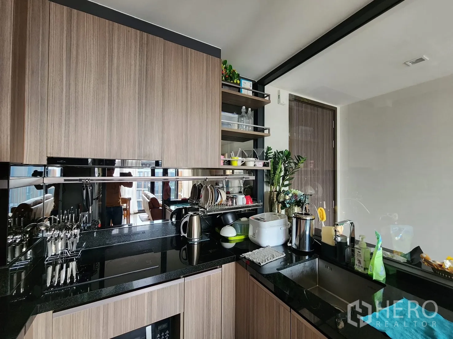 Condominium for rent in Watthana, Bangkok - Contemporary kitchen with black granite countertops, wood cabinets, stainless sink, and induction cooktop.
