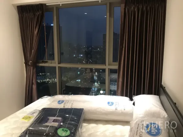 公寓 出租在Phra Khanong, Bangkok - 卧室设大窗与遮光窗帘，尽览城市天际线夜景。