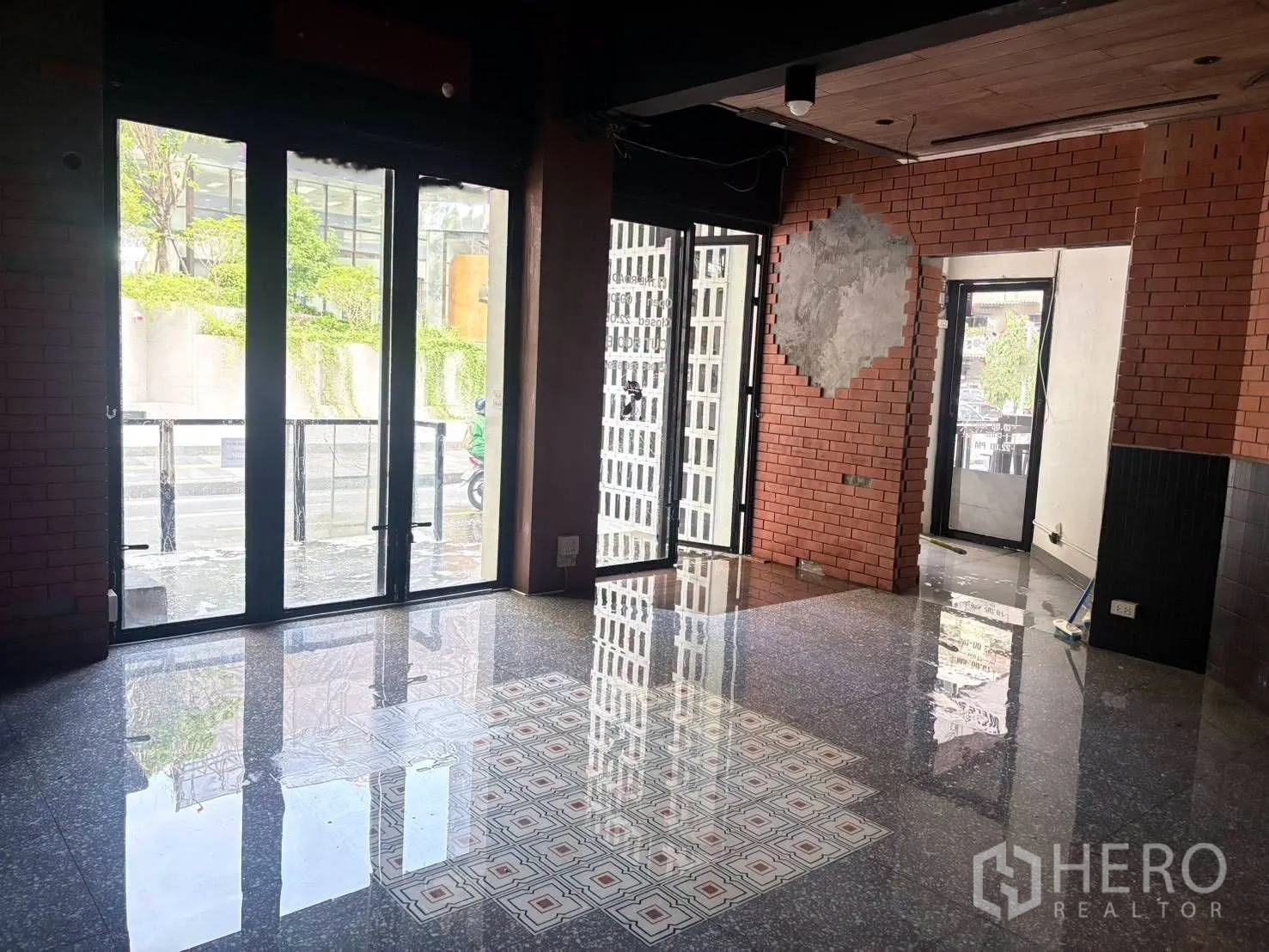 Retail Space for rent in Watthana, Bangkok - Bright retail space showing wide glass frontage, patterned tile inlay on polished floor, and a corner layout with a secondary glass entrance.