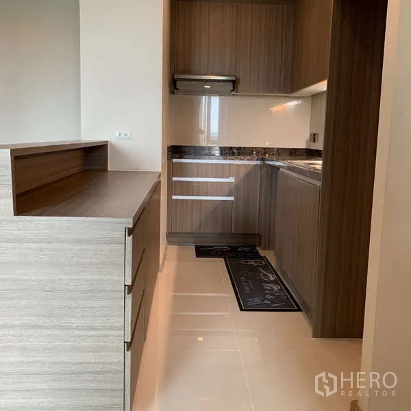 คอนโด ให้เช่า - ครัวรูปทรงแคบยาว ตู้ลายไม้ เครื่องดูดควัน และพื้นกระเบื้องมันวาว