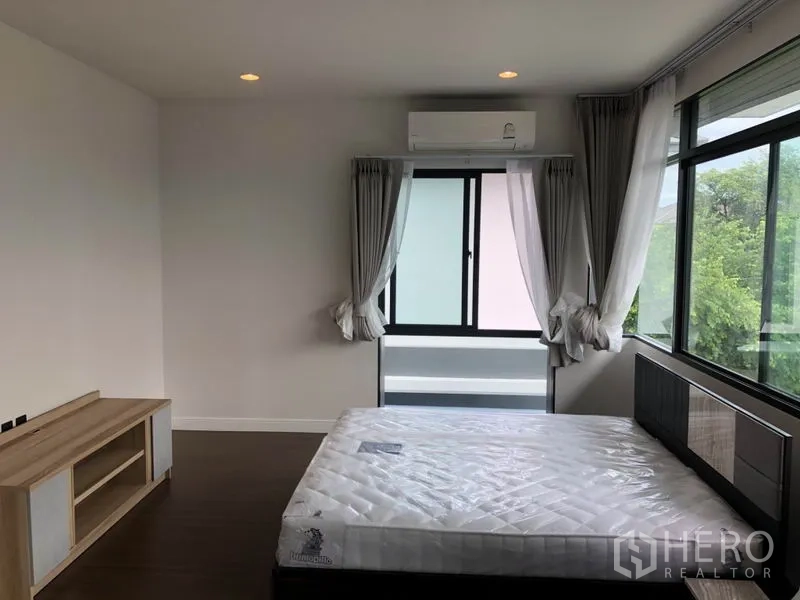 Detached House for rent or sale in Bang Kapi, Bangkok - Spacious master bedroom with large windows, bed and garden views.