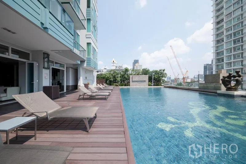 公寓 出租在Watthana, Bangkok - 室外游泳池配木平台与躺椅，城市景致环绕。