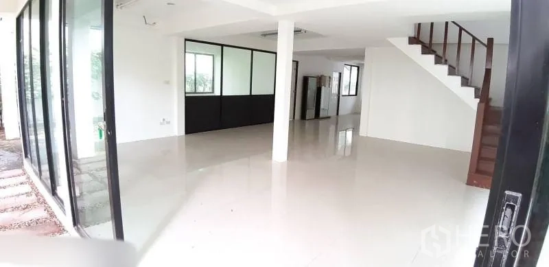 Detached House for rent in Prawet, Bangkok - Bright open-plan living area with glossy white floors, staircase and large sliding glass doors.