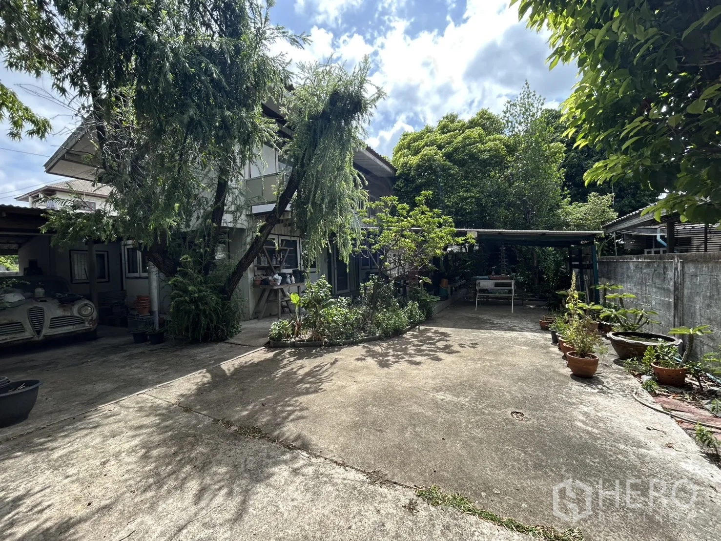 独栋房屋 for sale in Phra Khanong, Bangkok - 房屋正面，摆放盆栽并设有车棚与铺装空地。