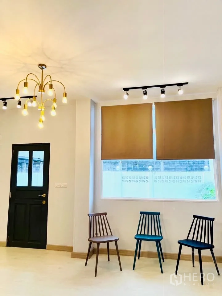 บ้าน ให้เช่า - มุมพักผ่อนพร้อมโคมแชนเดอเลียร์ ม่านม้วน และเก้าอี้ดีไซน์สี่ตัวริมหน้าต่าง