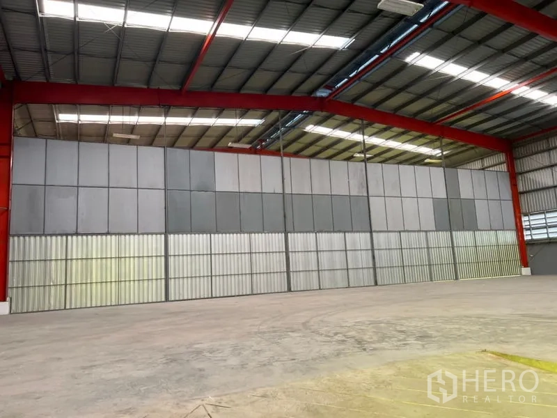 Warehouse for rent in Pathum Thani - Large internal sliding wall panels beneath a red steel frame with roof lights.