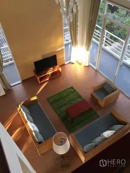 公寓 出租在Chatuchak, Bangkok - 自上而下俯瞰明亮客厅，藤制沙发、电视柜与落地窗。