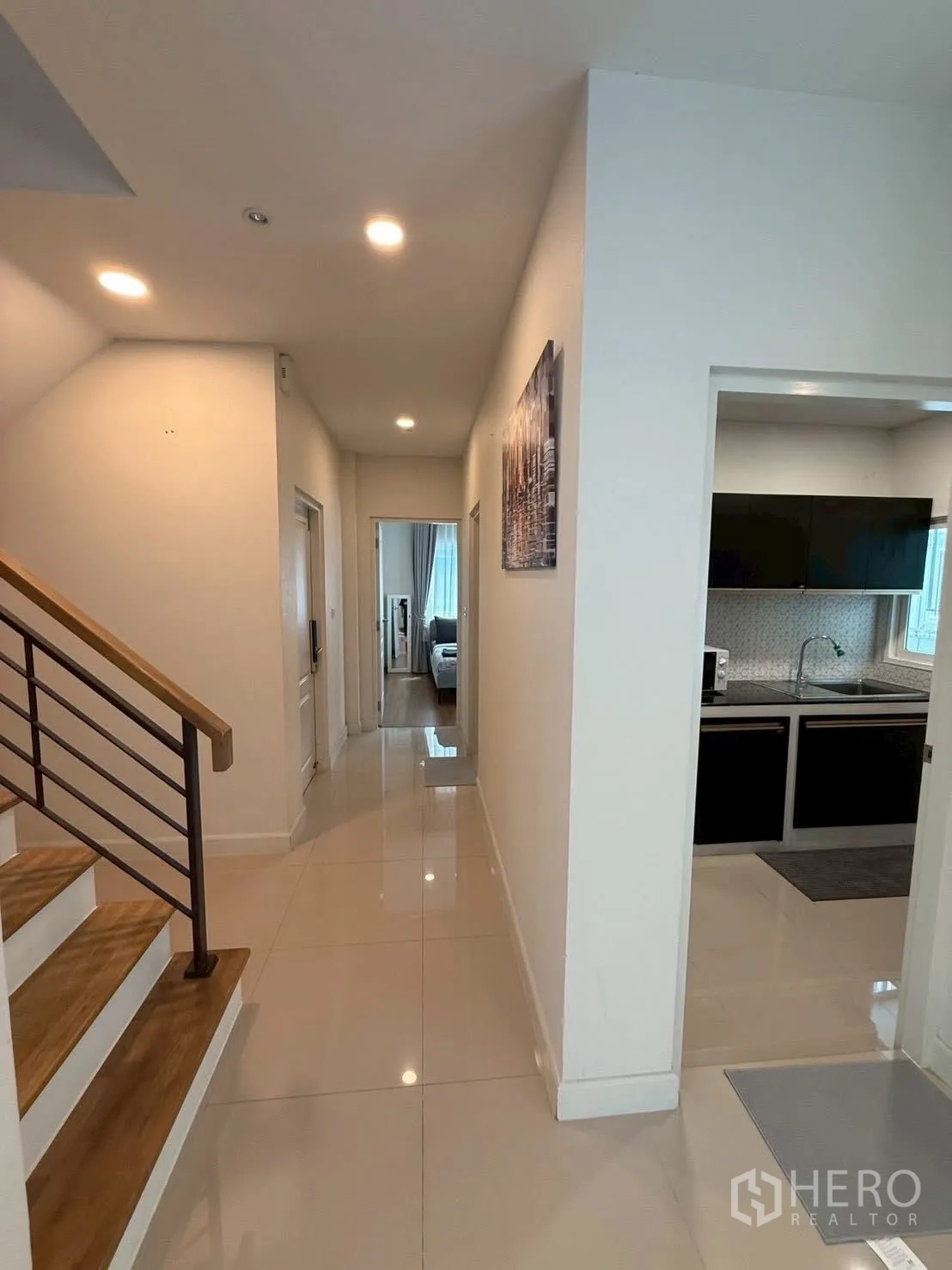 Detached House for rent in Prawet, Bangkok - Hallway with wooden staircase, recessed lights and doorways to the kitchen and bedroom.