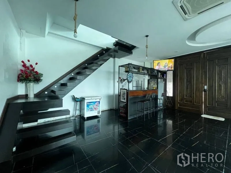 บ้าน ขายในLat Phrao, Bangkok - โถงพร้อมเคาน์เตอร์บาร์ บันไดลอย และประตูไม้แกะสลักบานใหญ่