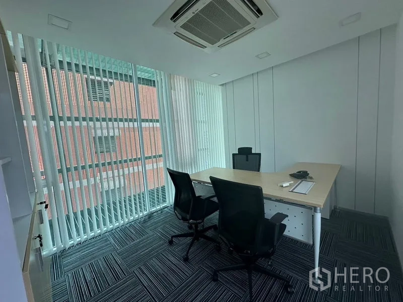 Office Space for rent - Executive office with window blinds, L-shaped desk and two guest chairs.
