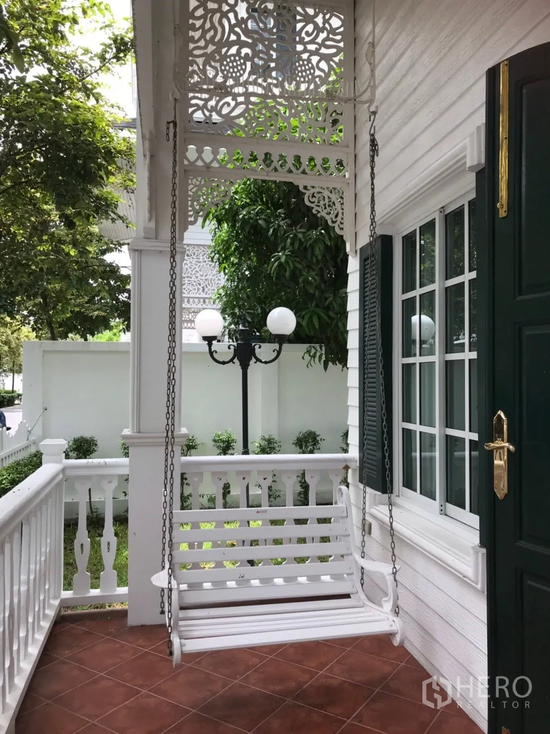 Detached House for rent in Mueang Samut Prakan, Samut Prakan - Covered front porch with a hanging white swing seat and decorative fretwork.