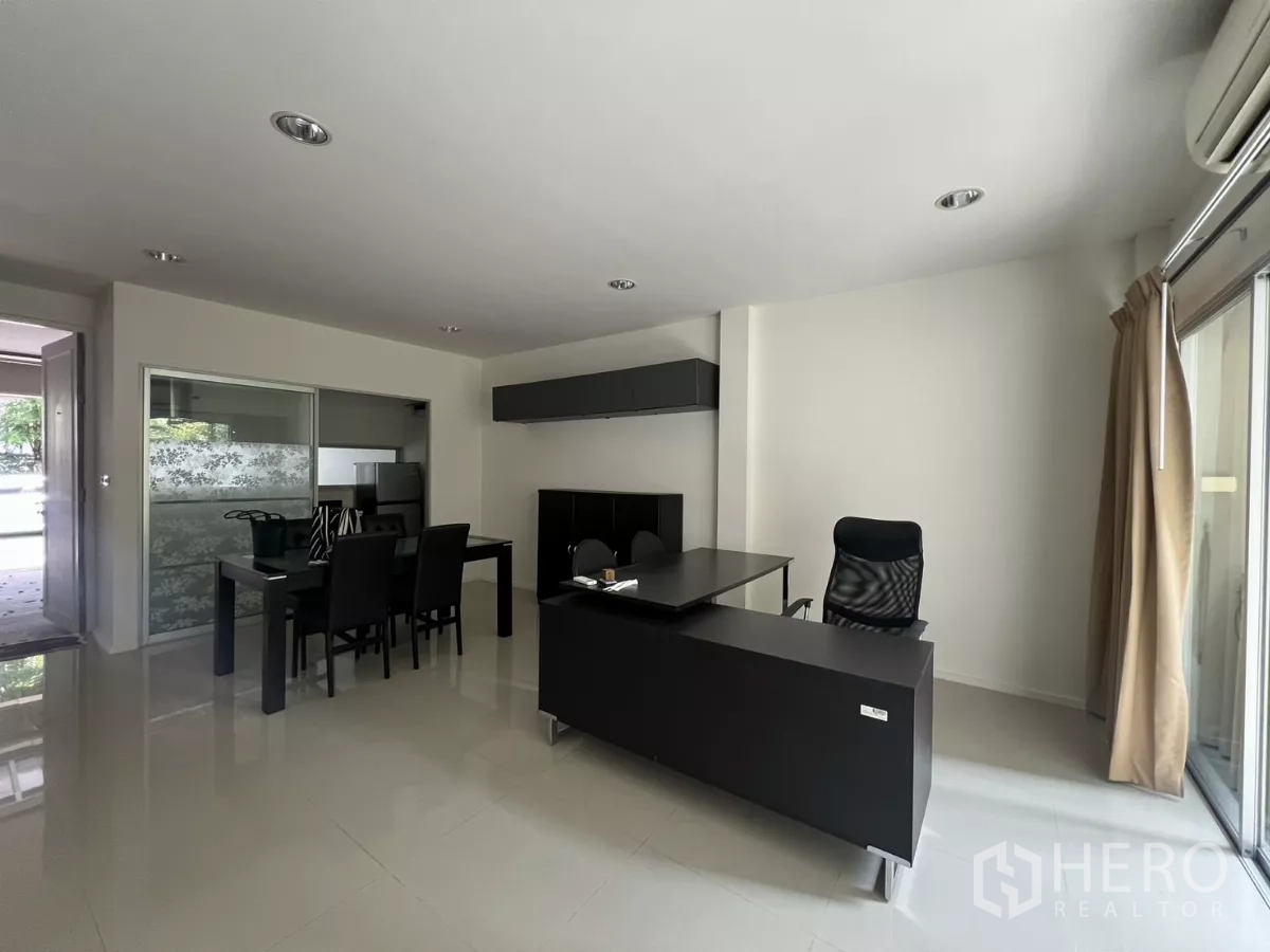Townhouse for rent in Suan Luang, Bangkok - Living room with desk and sliding doors opening to the patio garden.