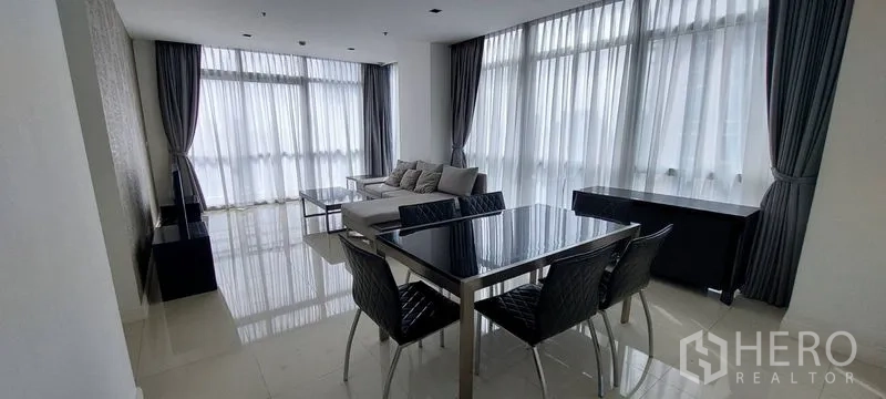 คอนโด ให้เช่าในPathum Wan, Bangkok - พื้นที่นั่งเล่นและทานอาหารแบบเปิดโล่ง หน้าต่างสูงจรดเพดาน ผ้าม่านโปร่ง พื้นแกรนิตเงา ชุดโต๊ะอาหารสีดำและโซฟา