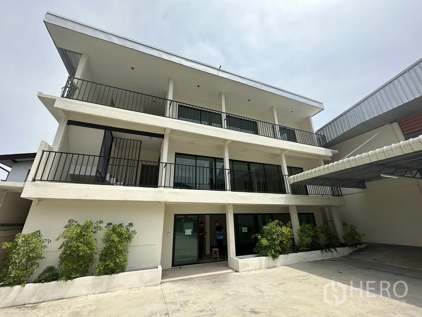 货栈 出租在Suan Luang, Bangkok - 现代三层办公楼立面，带阳台与绿植。