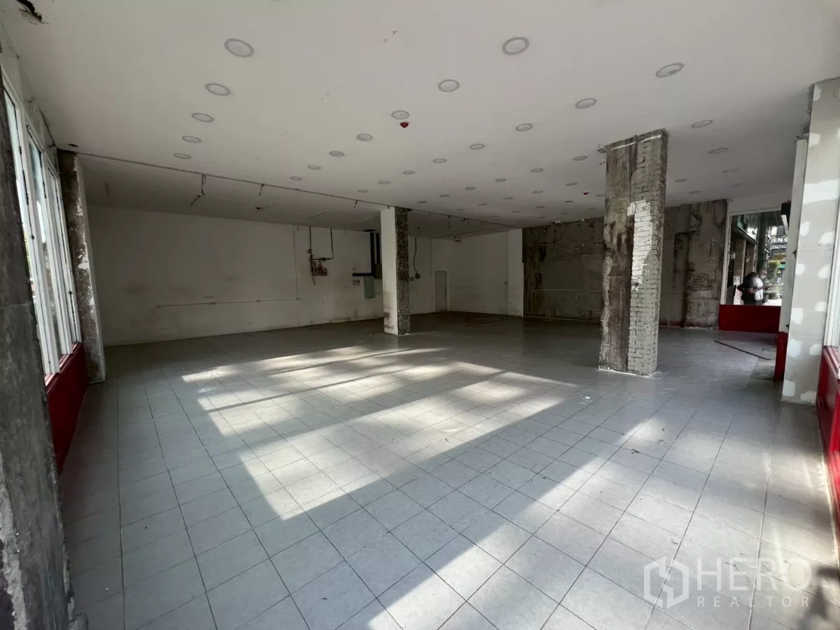 พื้นที่ขายปลีก ให้เช่า - พื้นร้านกว้างปูกระเบื้อง ไฟสปอตไลท์เพดาน และเสาโชว์คอนกรีต
