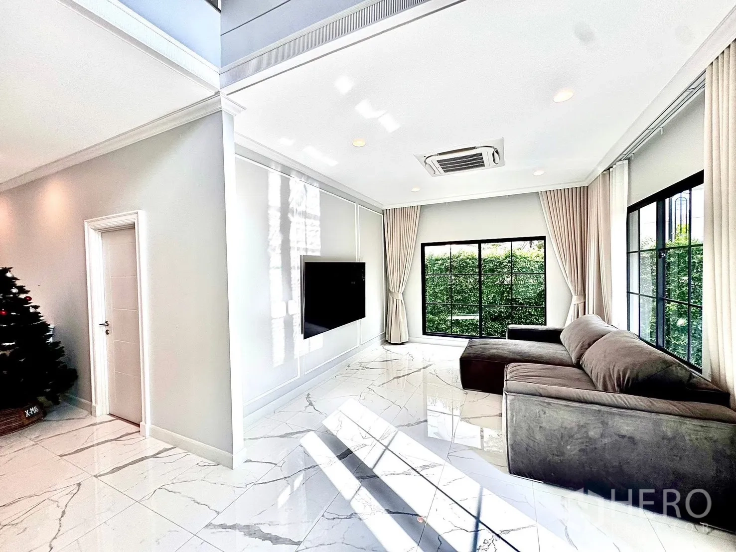 Detached House for rent in Bang Phli, Samut Prakan - Bright living room with marble-look tiles, L-shaped sofa and wide garden-facing windows.