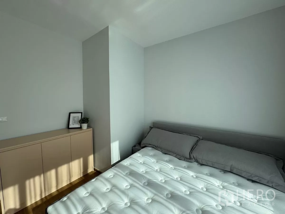 Townhouse for rent in Bang Phli, Samut Prakan - Sunlit bedroom corner with bed, low cabinet, and soft gray tones