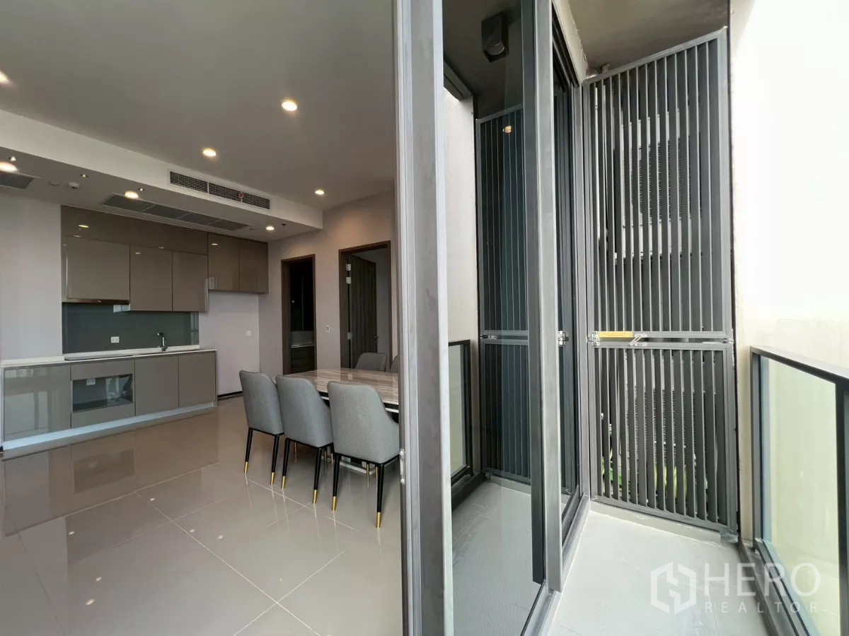Condominium for rent in Phra Khanong, Bangkok - Balcony entrance beside dining area and open kitchen with sliding glass doors.
