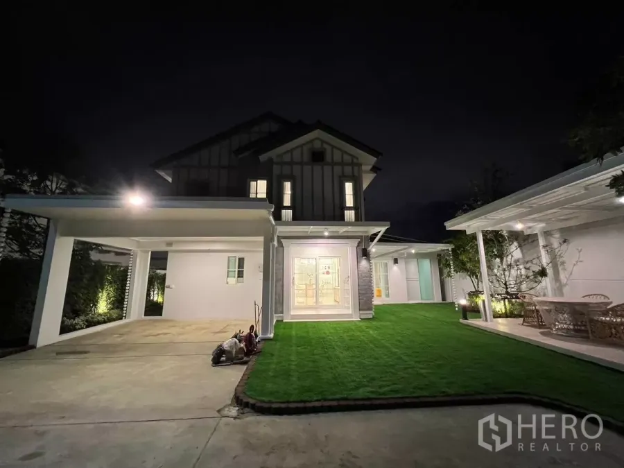 Detached House for rent in Bang Phli, Samut Prakan - Night view of a two-storey detached house with dual carports, manicured lawn and patio lighting.