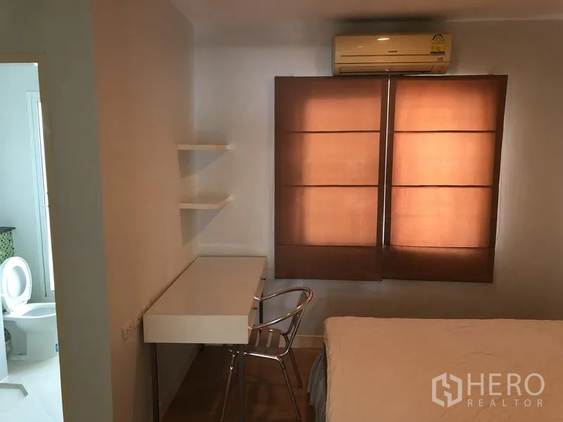 联排别墅 出租在Prawet, Bangkok - 紧凑卧室，书桌搁架、空调与连接浴室的门。