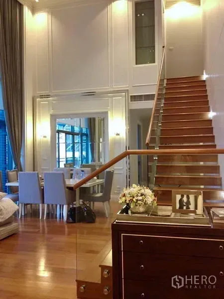 คอนโด ให้เช่าหรือขายในKhlong Toei, Bangkok - ห้องนั่งเล่นเพดานสูงพร้อมบันไดไม้ ชุดรับประทานอาหาร และหน้าต่างสูงจรดเพดาน