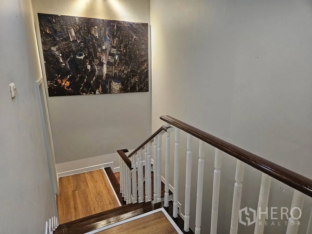 联排别墅 for rent in Yan Nawa, Bangkok - 楼梯平台，木扶手与大型城市夜景装饰画。