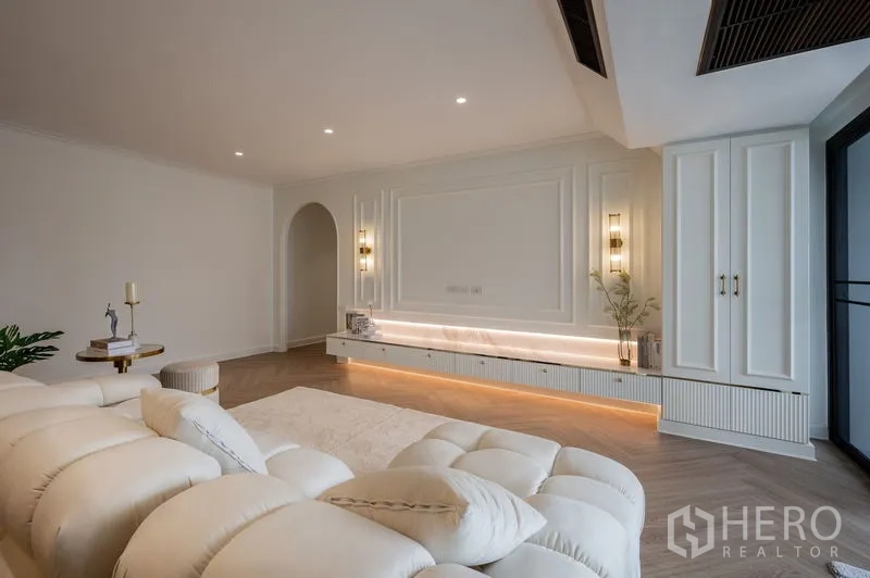 Condominium for sale in Watthana, Bangkok - Living room feature wall with built-in LED console and decorative sconces.