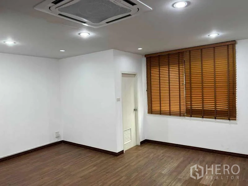 Home Office for rent in Bueng Kum, Bangkok - Corner office space with wood floors, window blinds and an internal door to bathroom or storage.